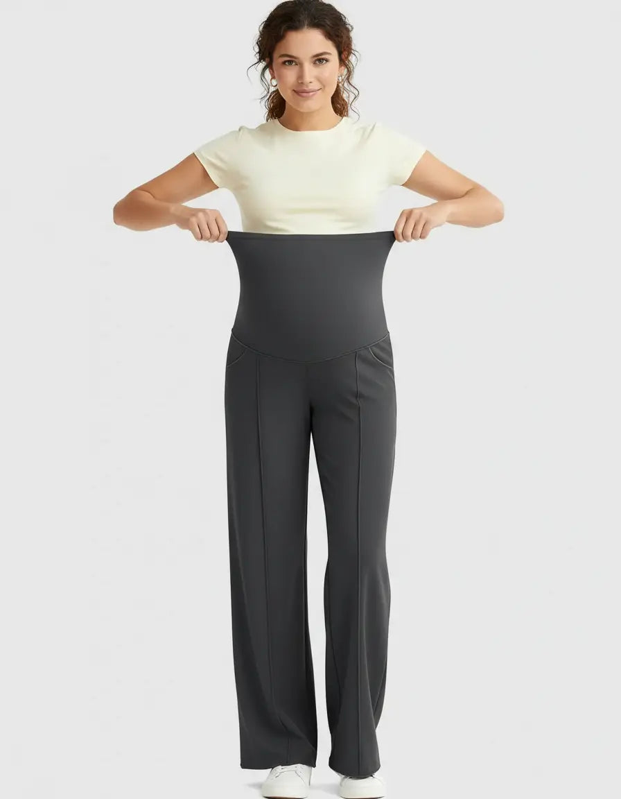 Woman in a cream top stretching the high-waist, relaxed-fit charcoal maternity pants to show flexibility.