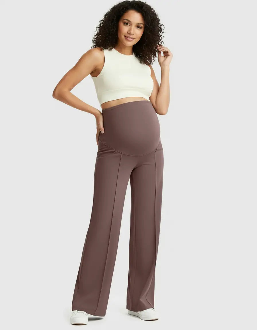 Woman in high-waist brown maternity pants with a relaxed fit and a cream crop top.