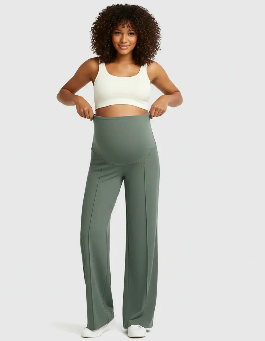 Smiling pregnant woman in a white crop top and olive green high-waist maternity pants with a relaxed, wide-leg fit.