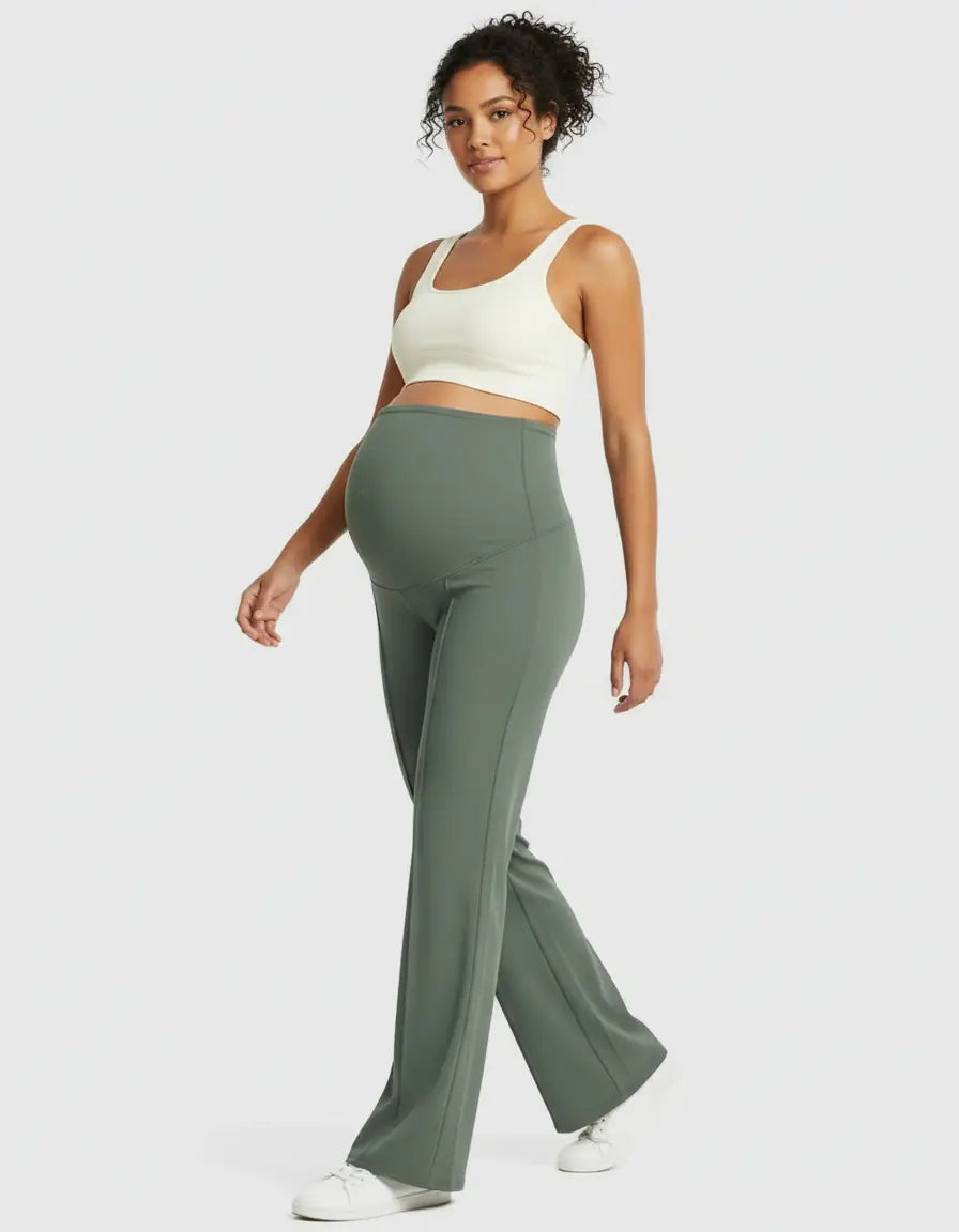 Pregnant woman in sage green high-waist maternity pants with a relaxed fit and a cream sports bra.