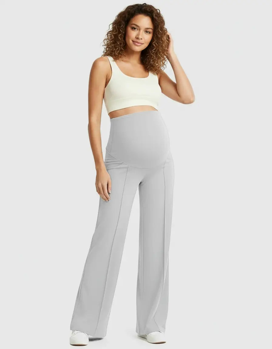 Smiling pregnant woman in light gray high-waist maternity pants with a relaxed fit and a cream crop top.
