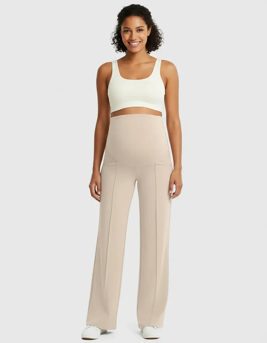 Smiling woman in beige high-waist maternity pants with a relaxed fit and a white crop top.