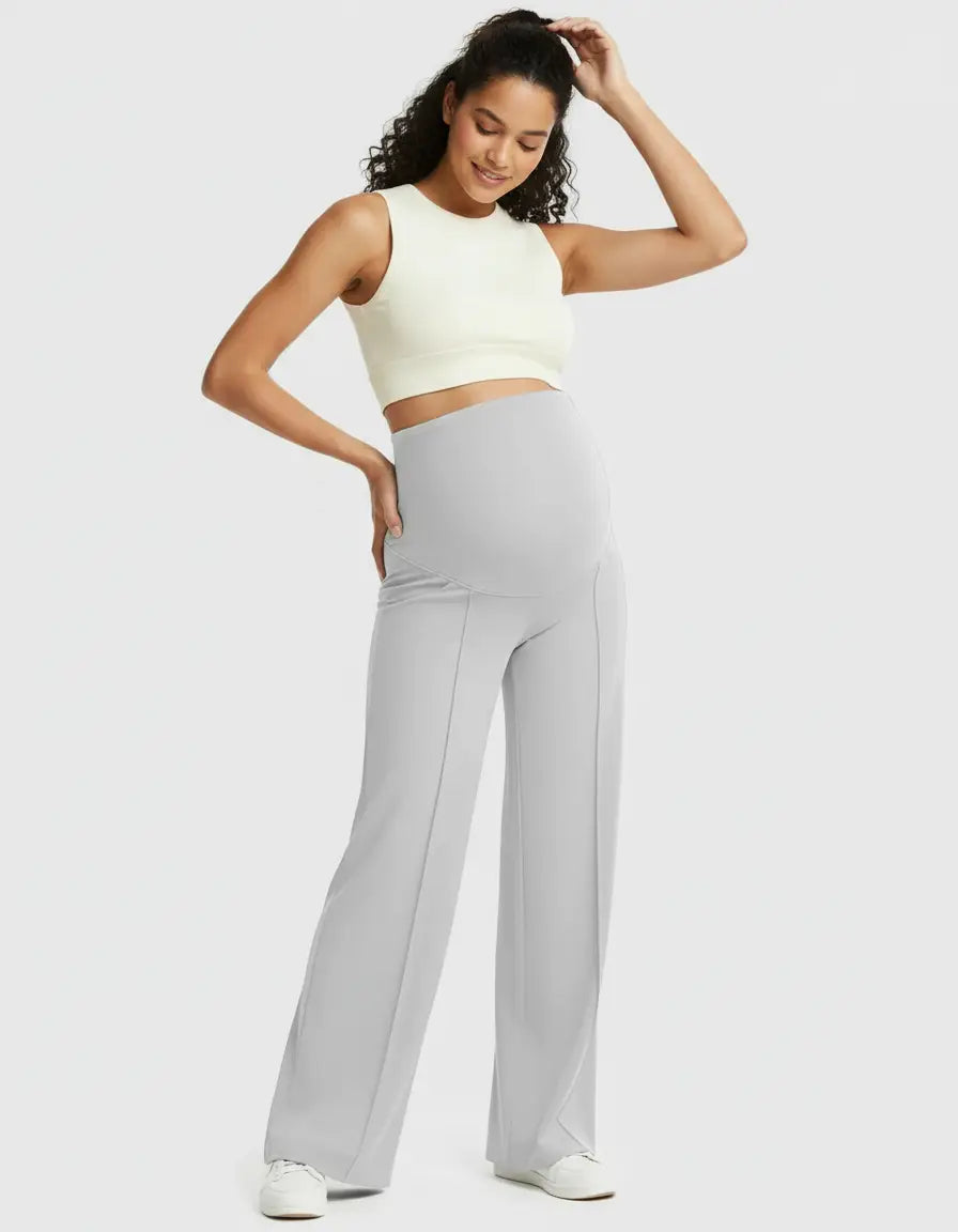 Smiling pregnant woman in light gray high-waist maternity pants with a relaxed fit and a cream crop top.