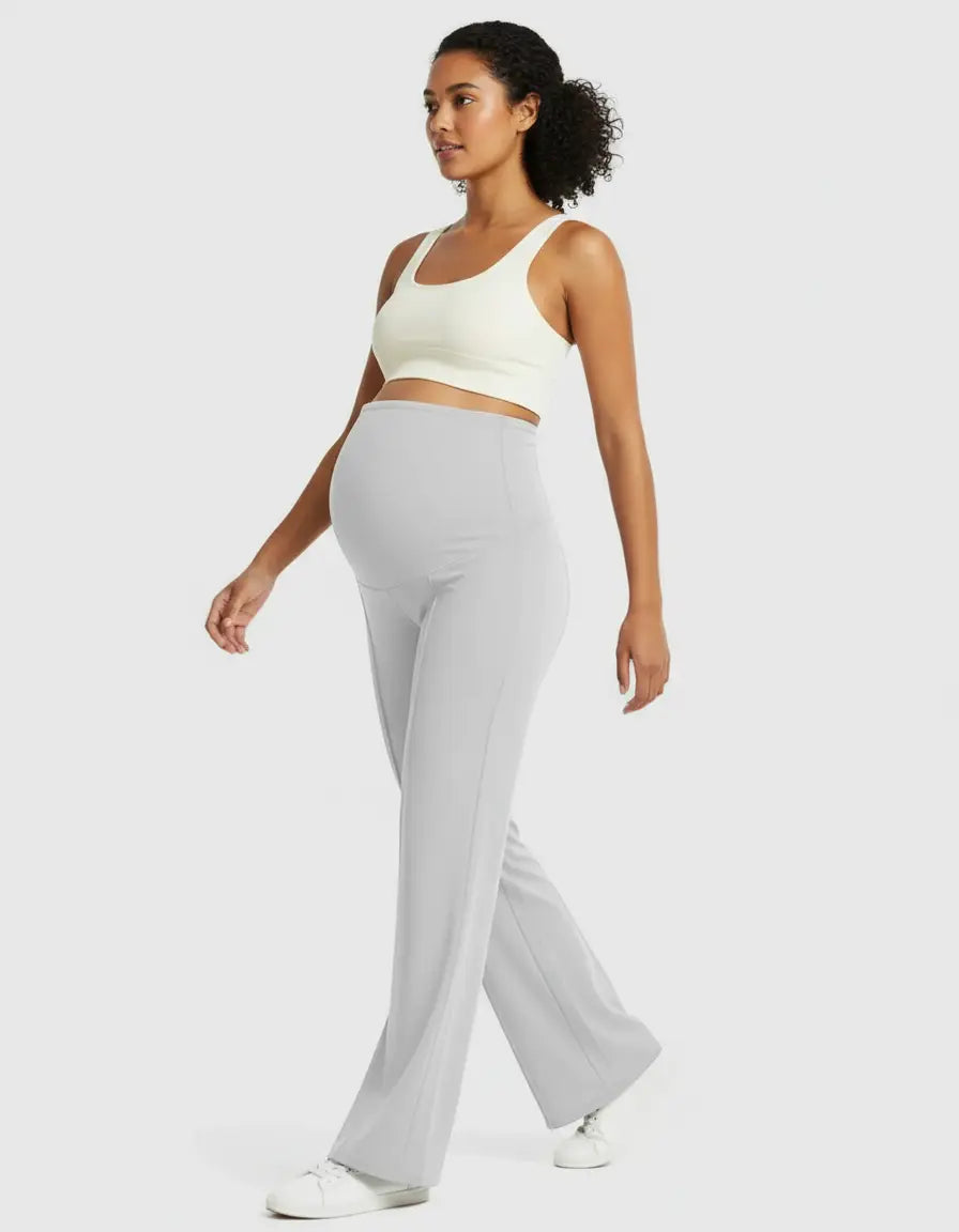 Pregnant woman in light grey high-waist maternity pants with a relaxed fit and a white crop top.