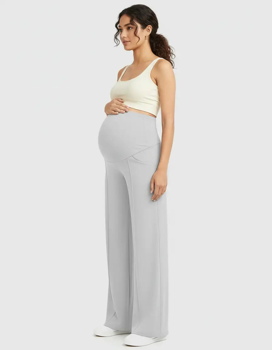 Pregnant woman in light grey high-waist maternity pants with a relaxed, wide-leg fit and a cream crop top.