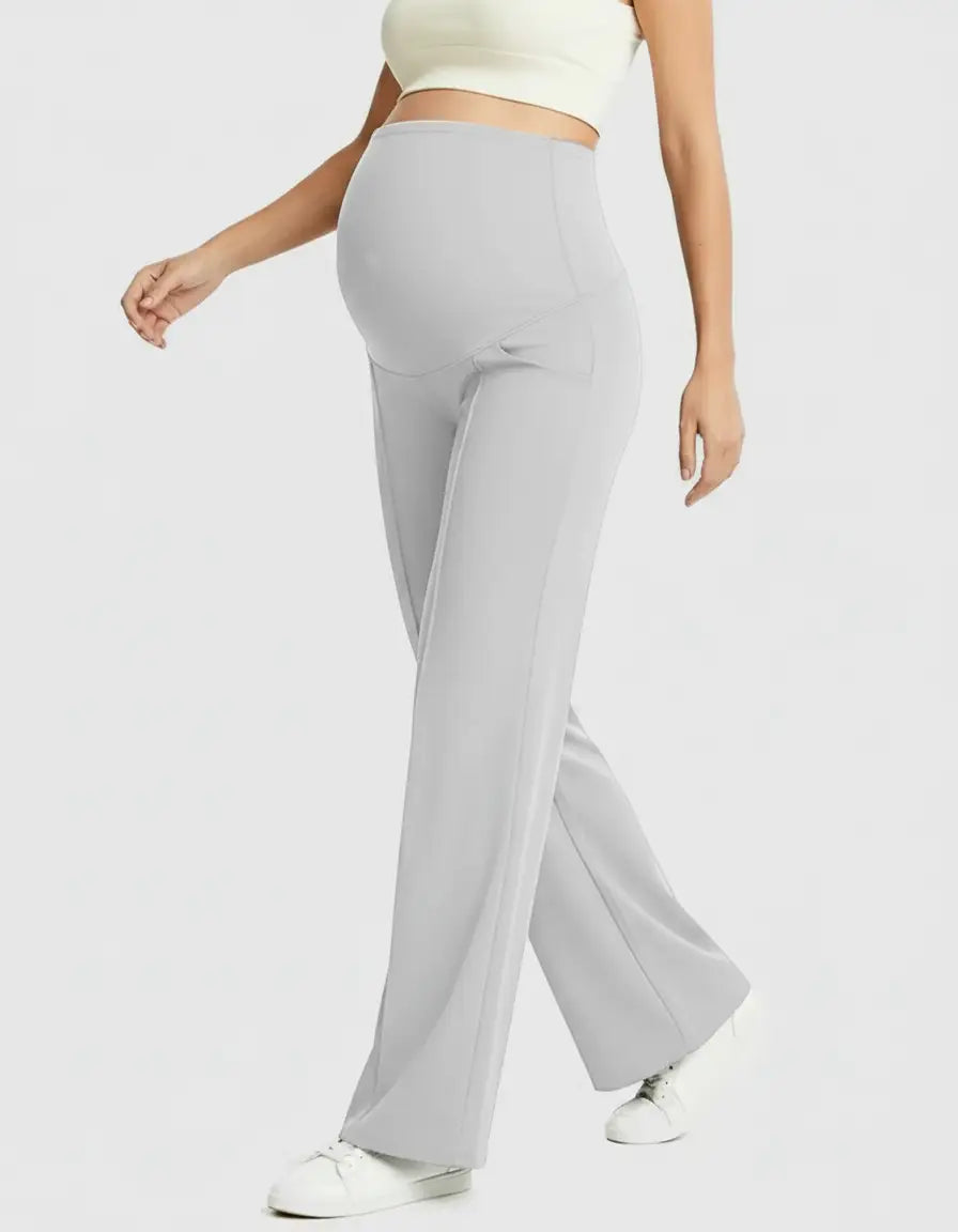 Pregnant woman in light grey high-waist maternity pants with a relaxed fit and wide leg, paired with a crop top.