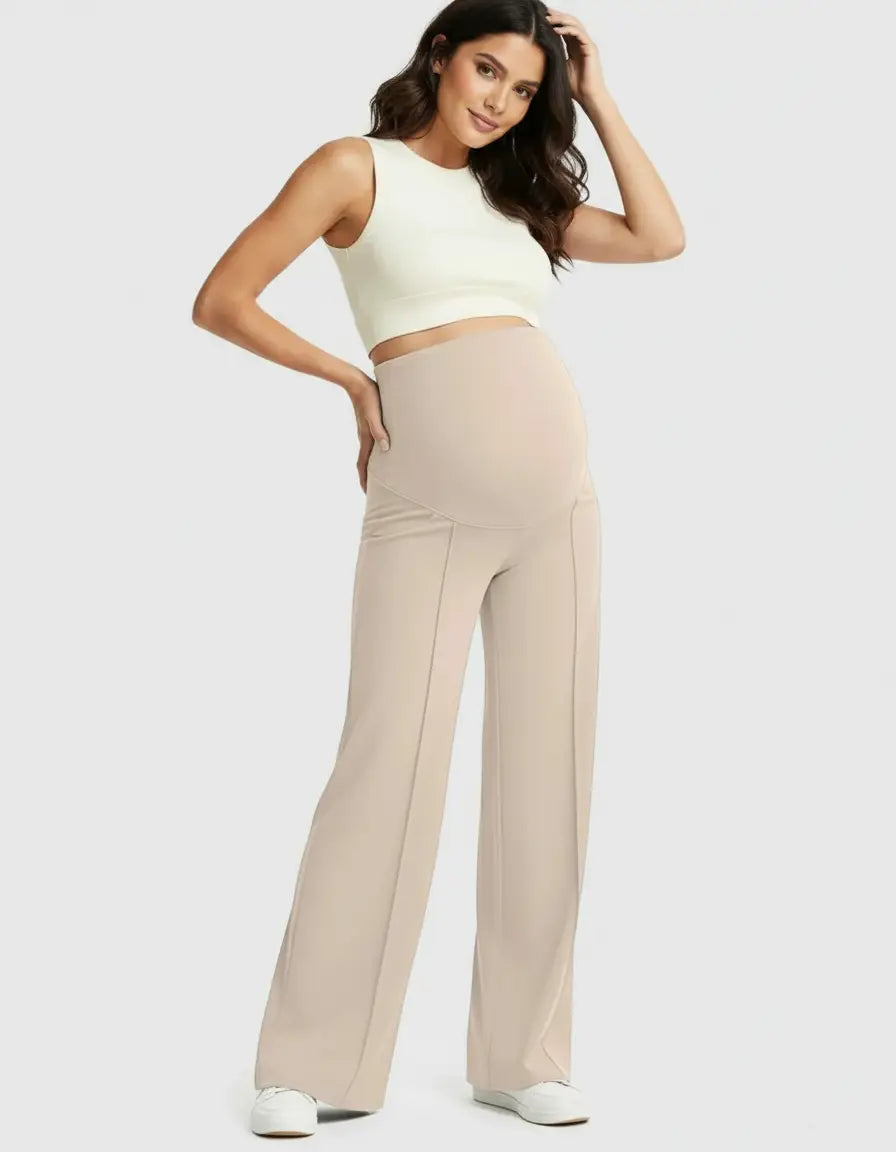 Smiling pregnant woman in beige high-waist maternity pants with a relaxed fit and a white crop top.
