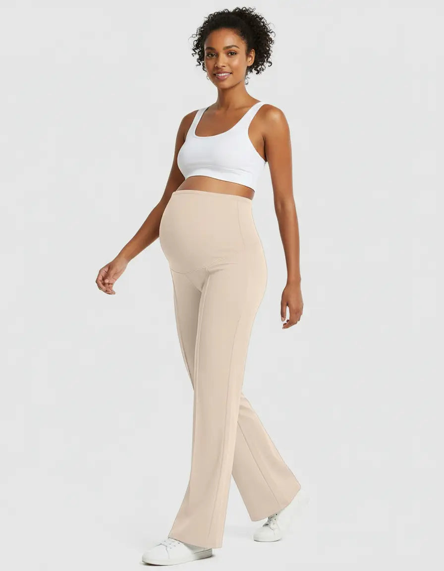 Smiling pregnant woman in high-waist, relaxed-fit beige maternity pants and a white crop top.