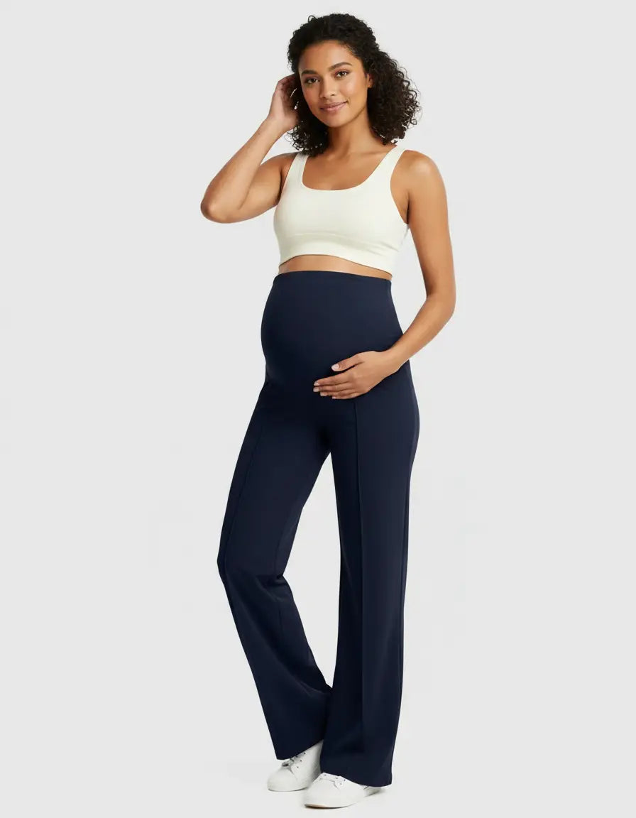 Smiling pregnant woman in navy high-waist maternity pants with a relaxed fit and a cream crop top.