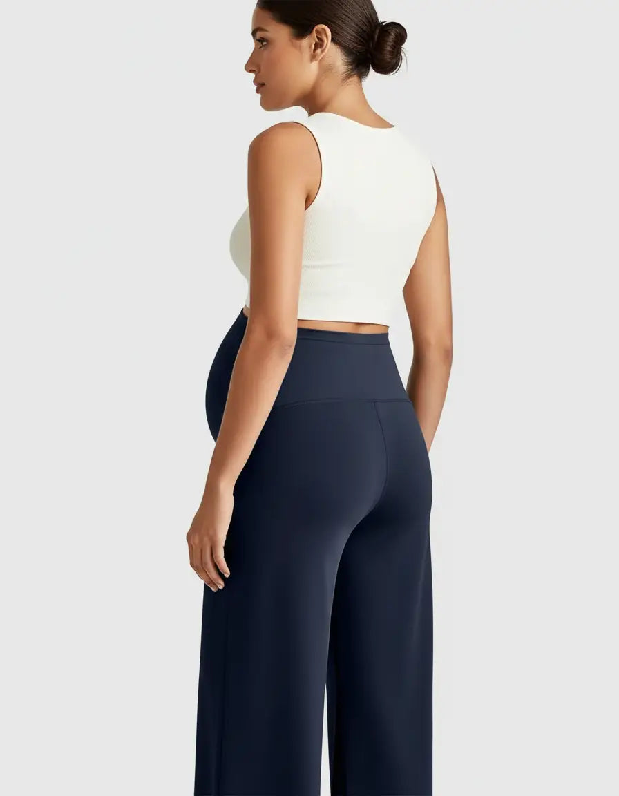 Pregnant woman in navy high-waist maternity pants with a relaxed fit and a white crop top.