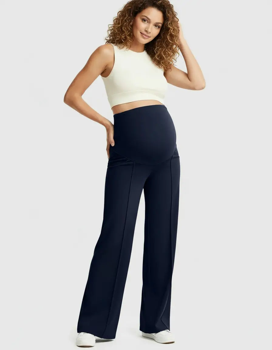 Smiling pregnant woman in navy high-waist maternity pants with a relaxed fit and a white crop top.