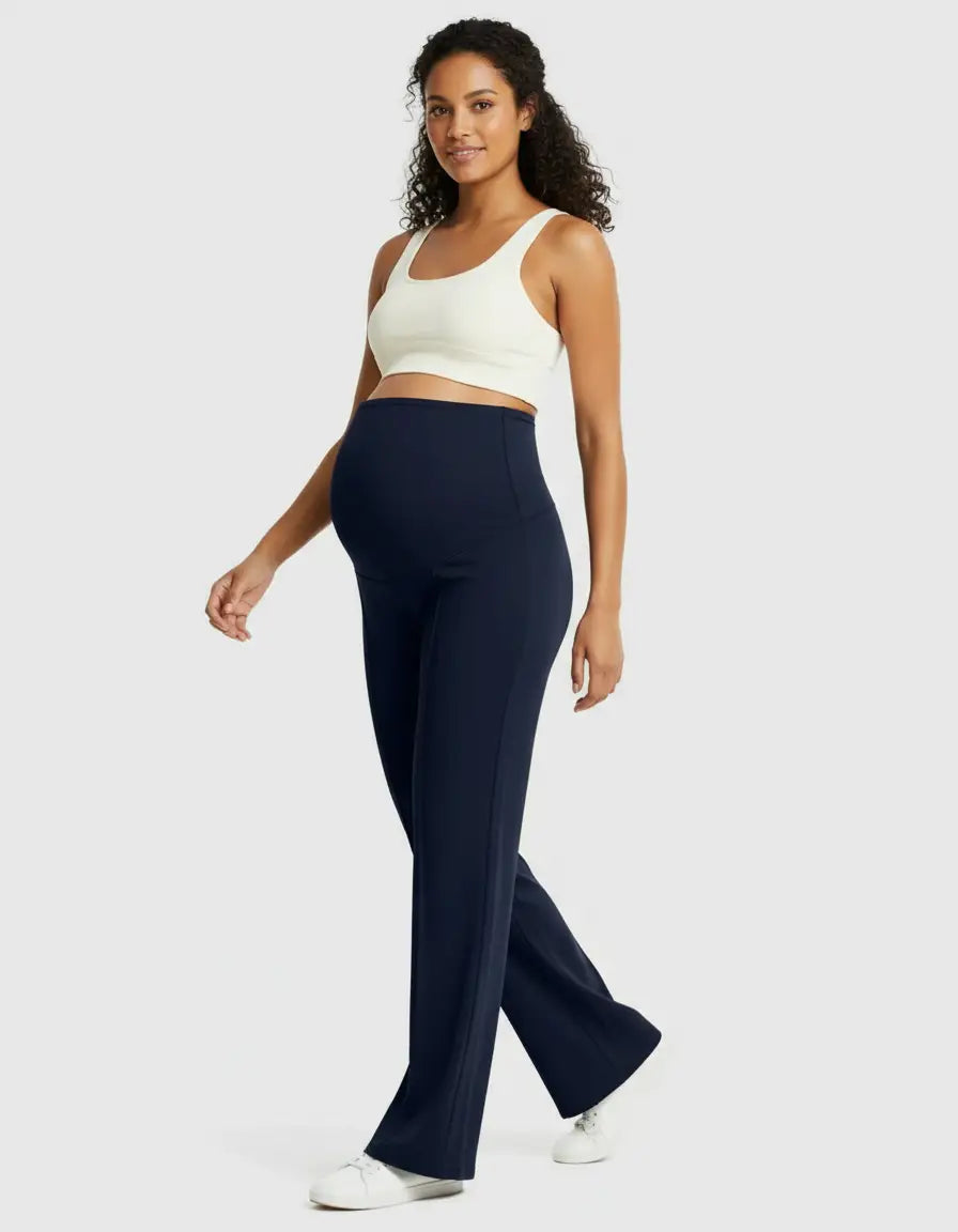 Smiling pregnant woman in navy high-waist maternity pants and a white crop top, walking.