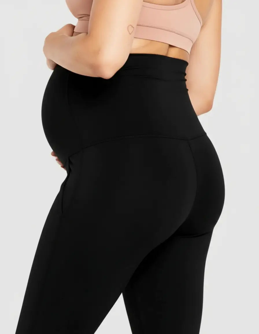 Pregnant woman in black high-waist pocketed flare-leg maternity leggings and a peach bra.