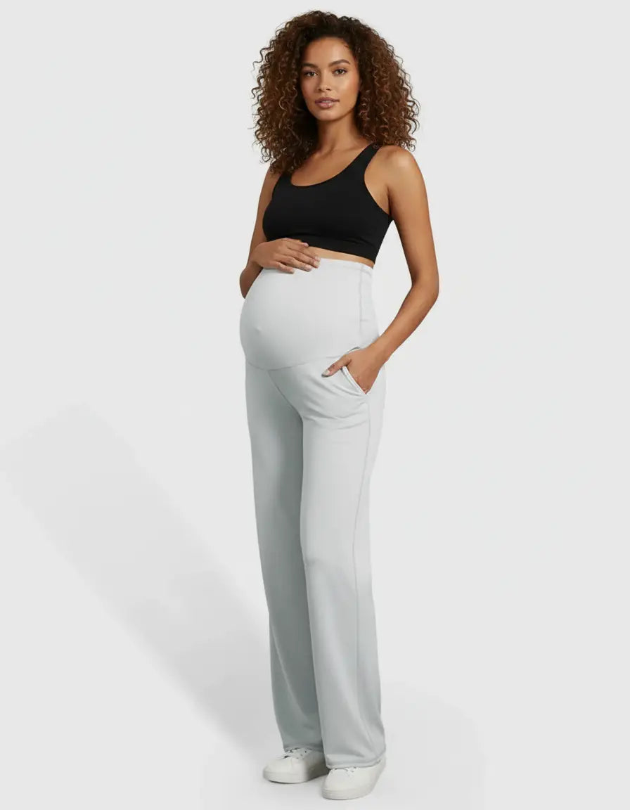 Pregnant woman in light gray high-waist straight-leg maternity pants with pockets and a black sports bra.