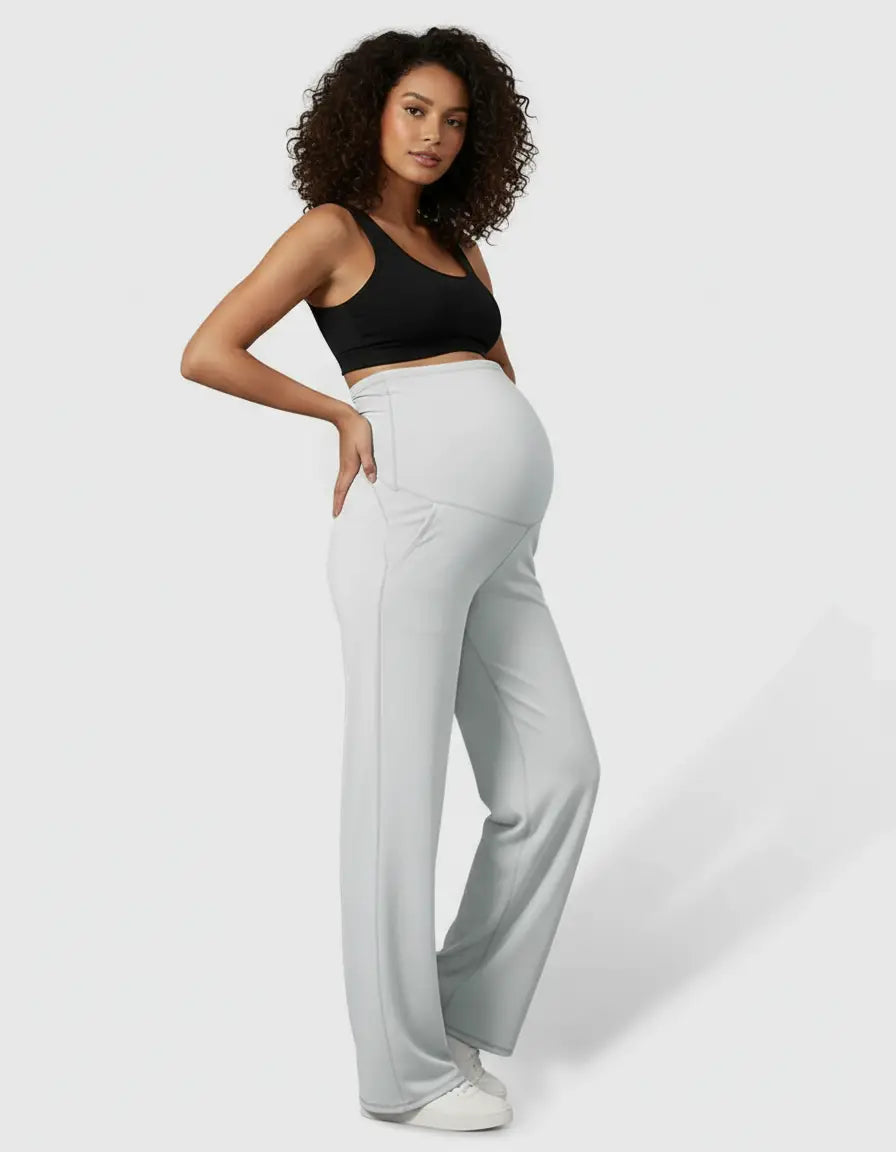 Pregnant woman in light grey high-waist straight-leg maternity pants and a black sports bra.