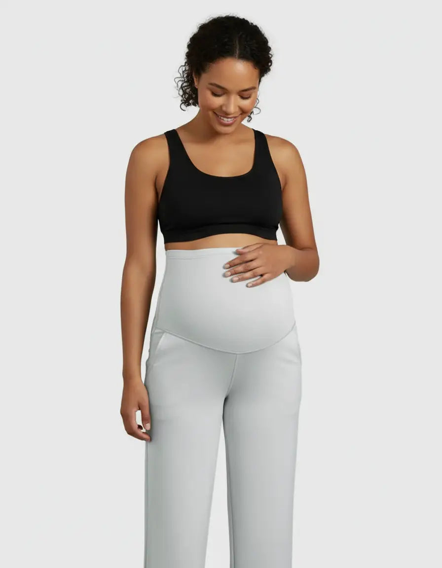 Smiling pregnant woman in a black bra and light gray high-waist straight-leg maternity pants.