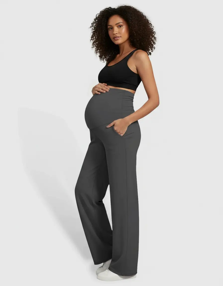 Pregnant woman in dark gray high-waist straight-leg maternity pants with pockets and a black crop top.