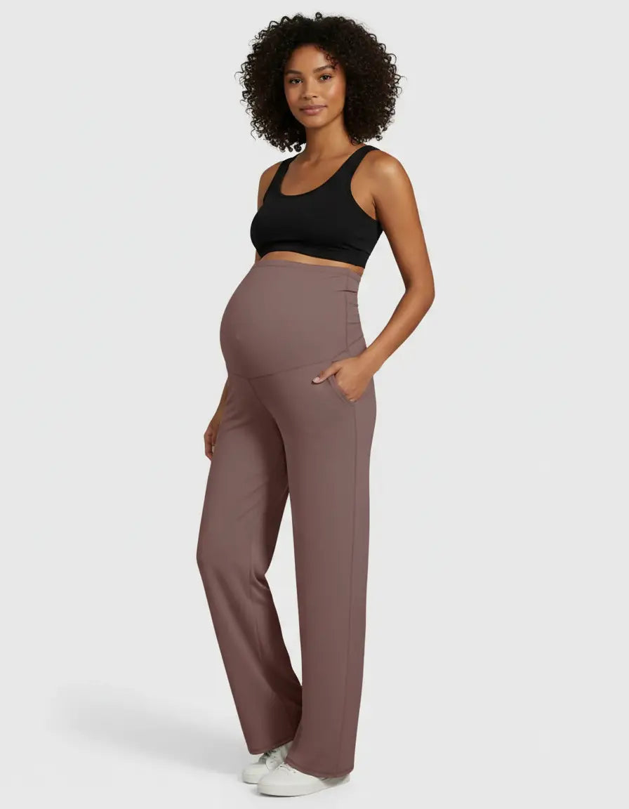 Pregnant woman modeling high-waist, straight-leg maternity pants in a soft, dusty rose color with pockets.