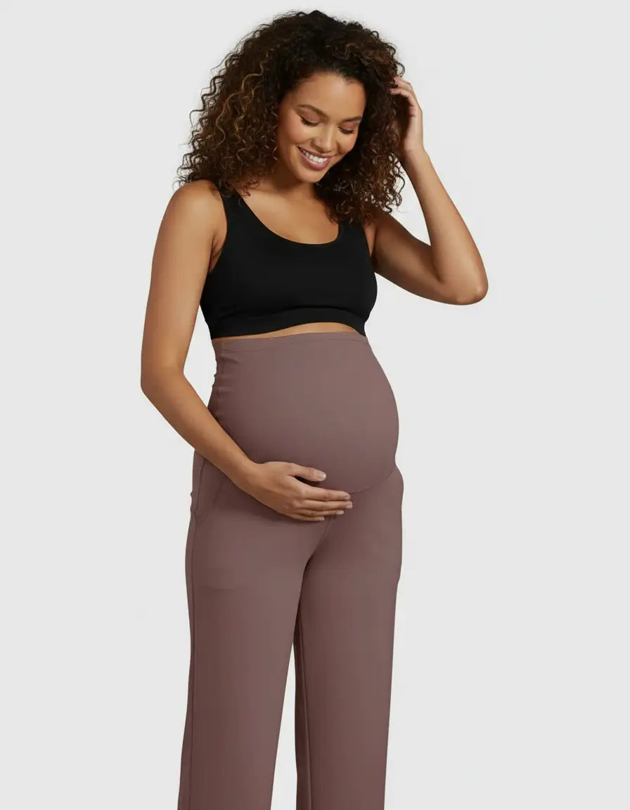 Smiling pregnant woman in high-waist, straight-leg maternity pants and a black bra.
