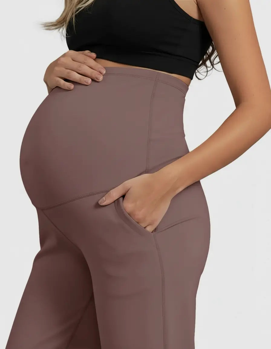 Pregnant woman in high-waist, straight-leg maternity pants in a soft, dusty rose color with side pockets.