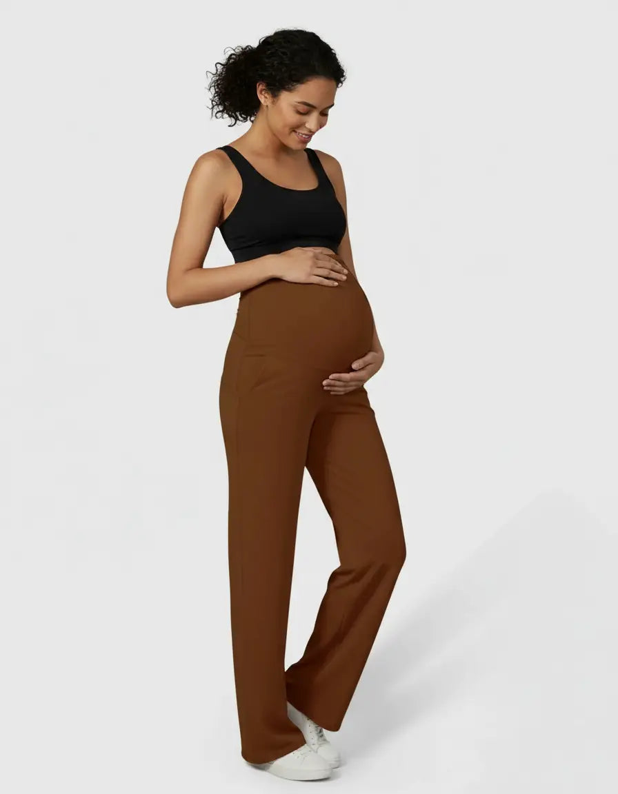 Smiling pregnant woman in brown high-waist straight-leg maternity pants and a black tank top.