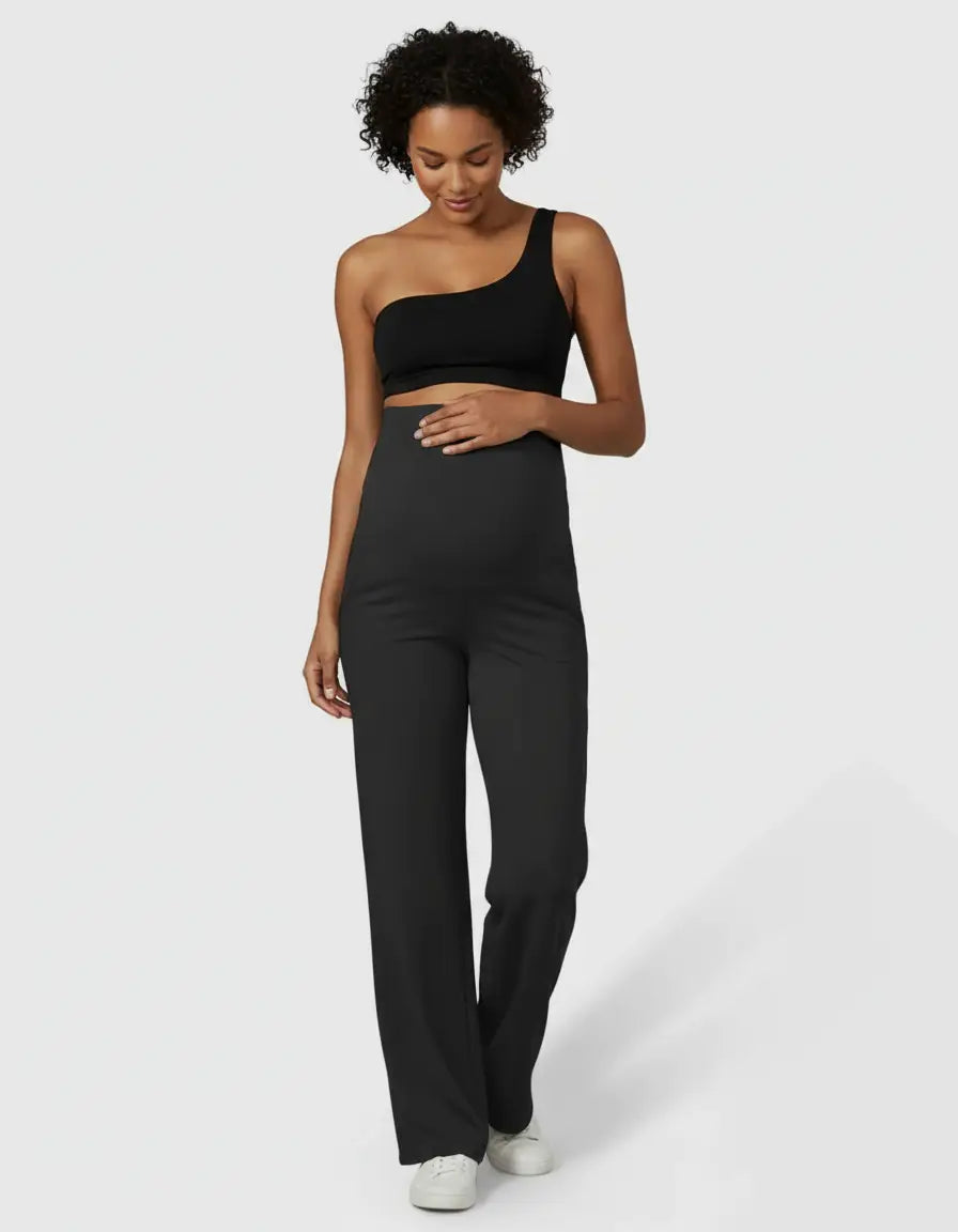 Pregnant woman in black high-waist straight-leg maternity pants and a black one-shoulder top.