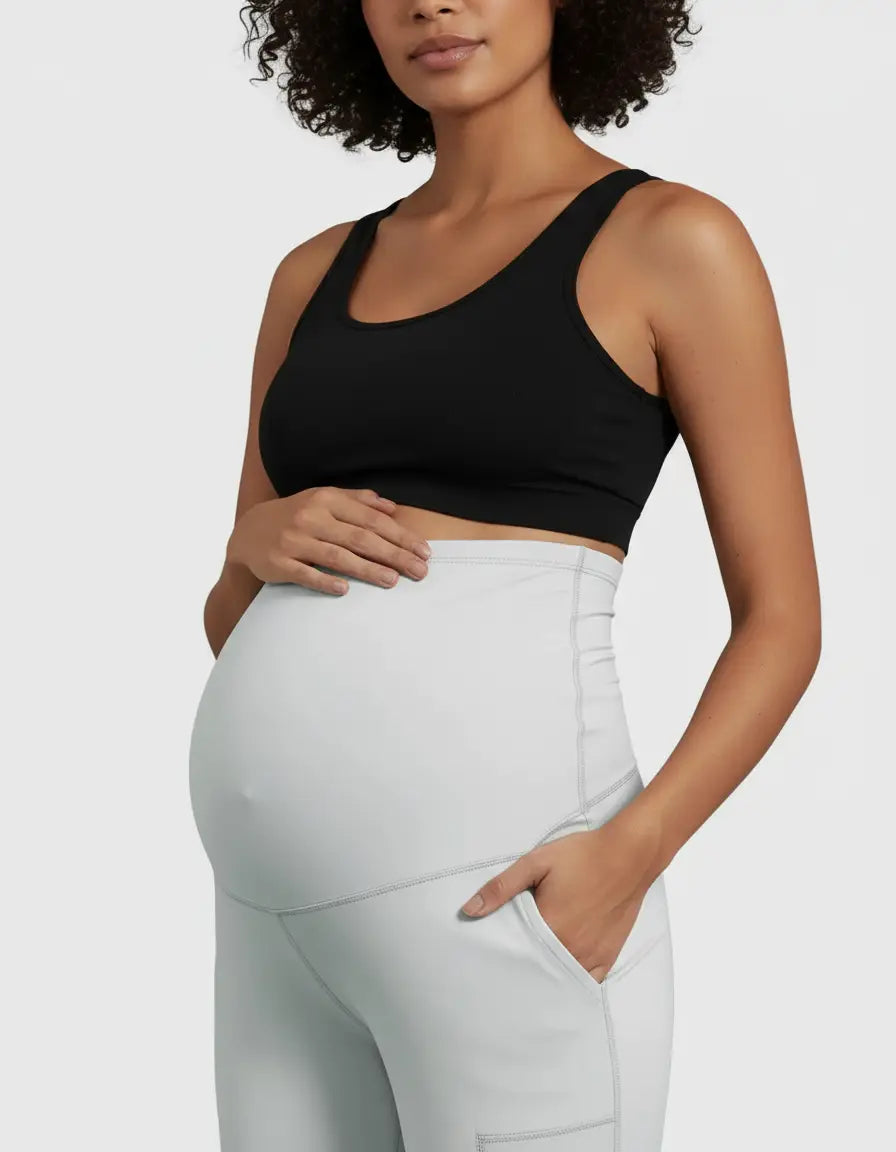 Pregnant woman in black sports bra and light grey high-waist straight-leg maternity pants with pockets.