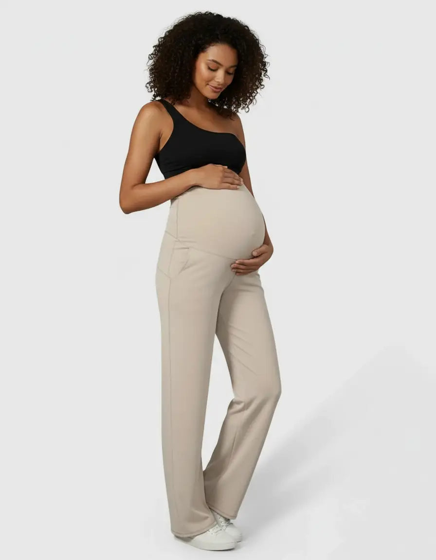 Pregnant woman in beige high-waist straight-leg maternity pants and a black one-shoulder top.