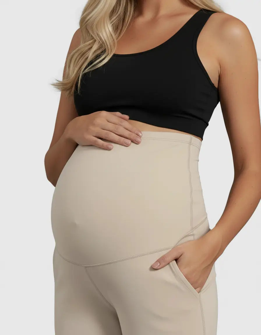 Pregnant woman wearing beige high-waist straight-leg maternity pants with a black sports bra.