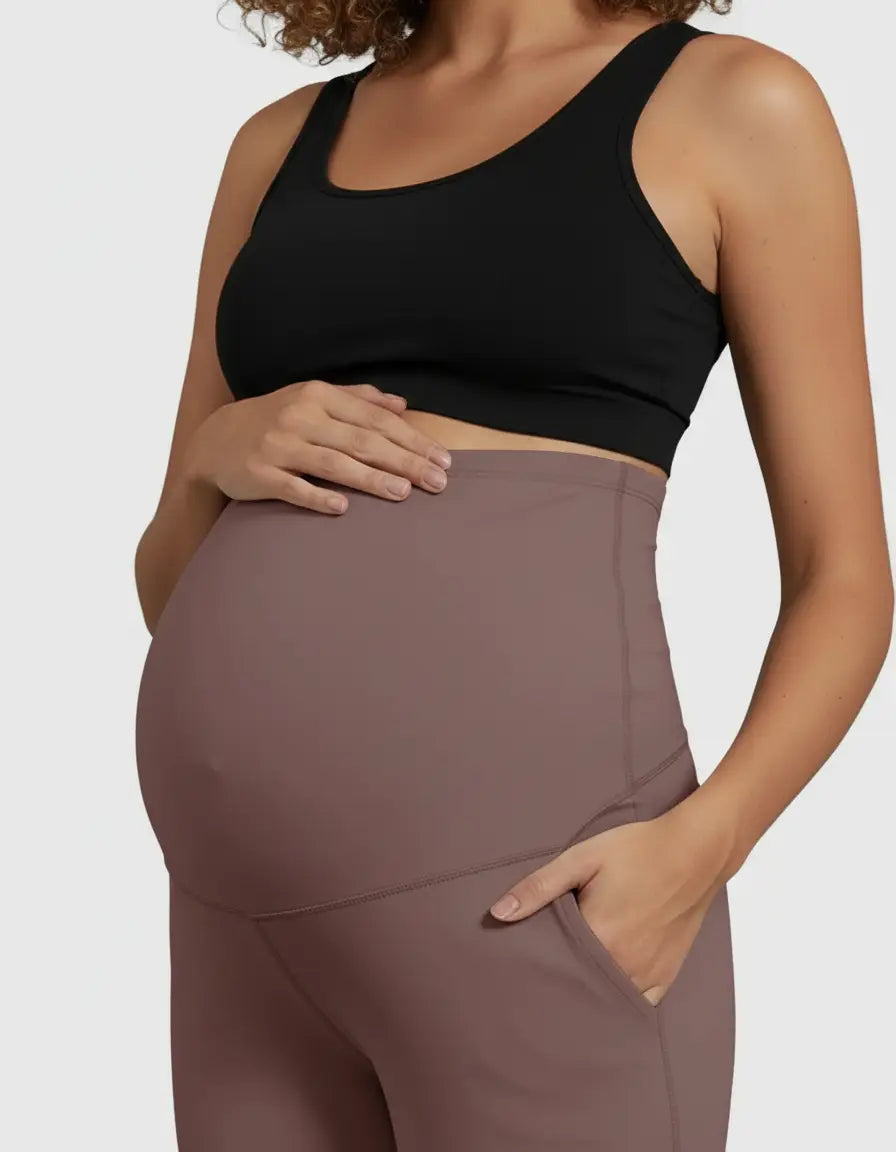 Pregnant woman wearing high-waist, straight-leg maternity pants in a soft, dusty rose color with pockets.