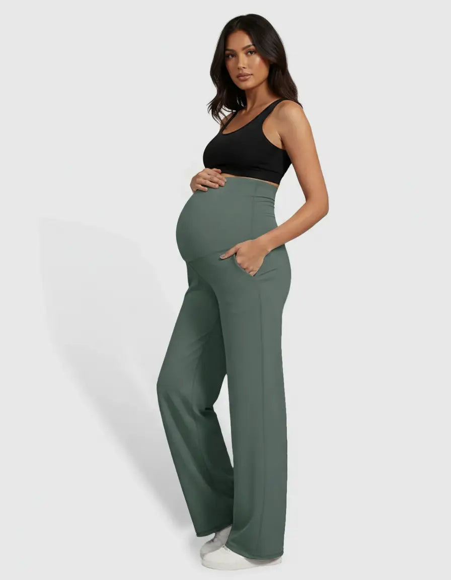 Pregnant woman in high-waist, straight-leg, sage green maternity pants with pockets and a black bra.