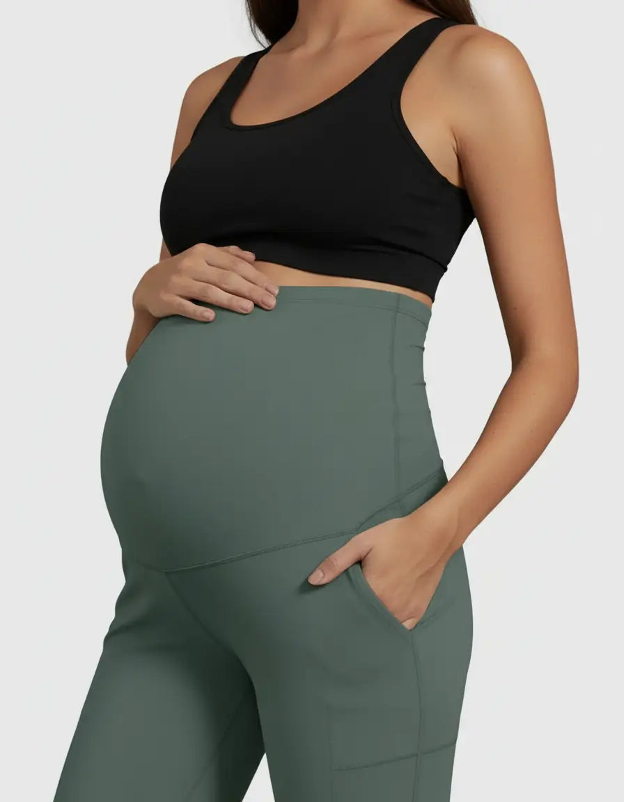 Pregnant woman in a black sports bra and sage green high-waist straight-leg maternity pants with pockets.