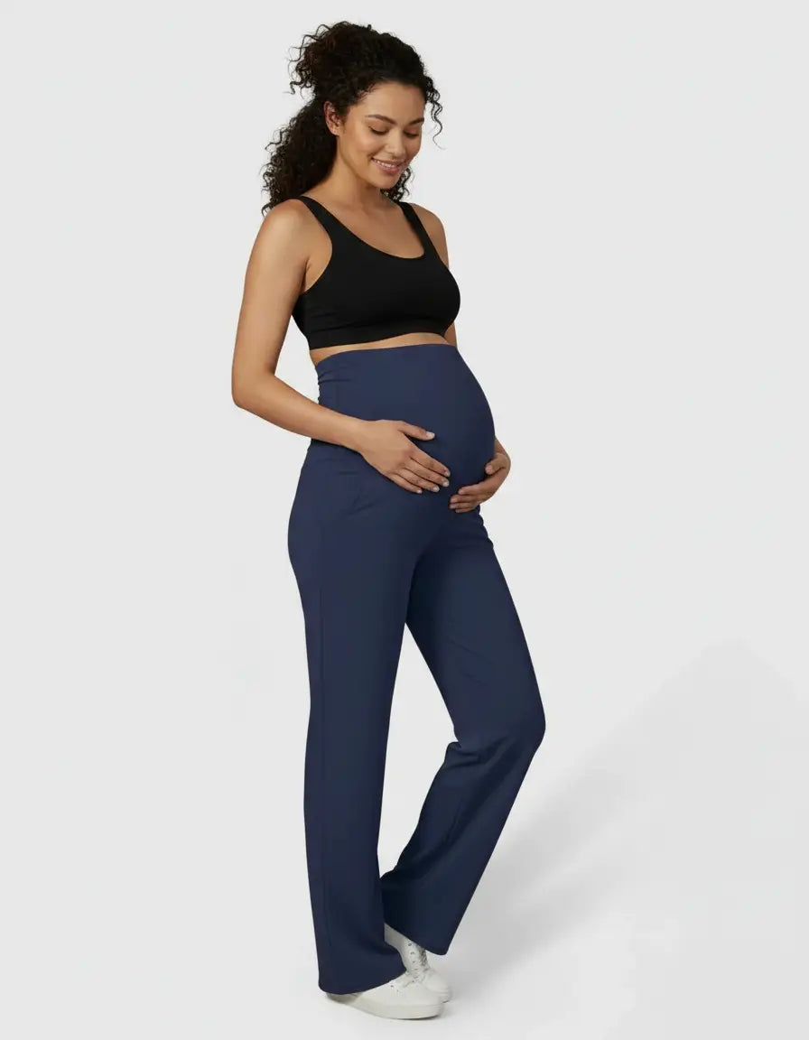 Smiling pregnant woman in navy high-waist straight-leg maternity pants and a black bra.