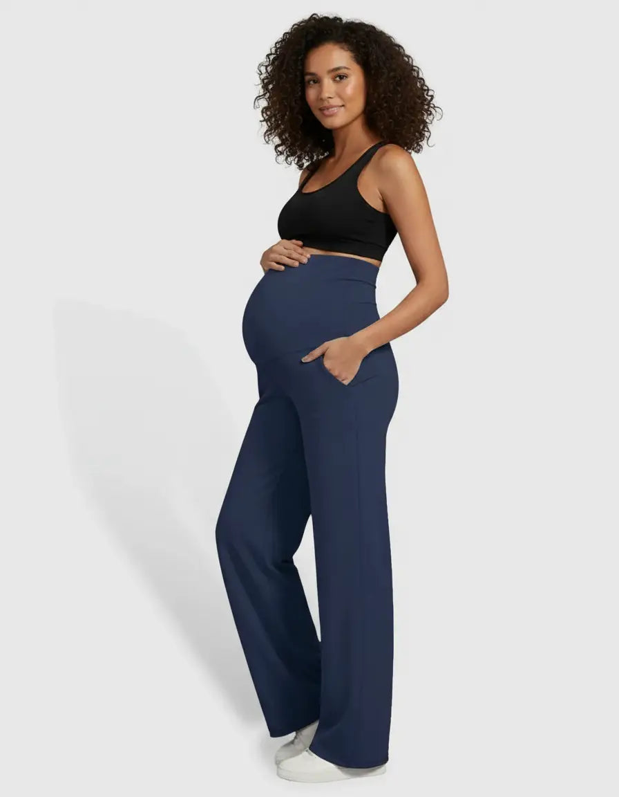 Pregnant woman wearing navy high-waist straight-leg maternity pants with pockets and a black crop top.