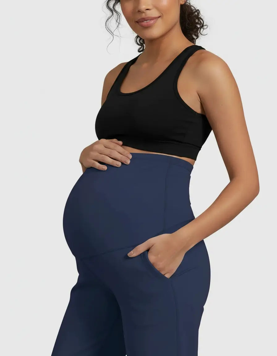 Pregnant woman in navy high-waist straight-leg maternity pants with a hand in the pocket.