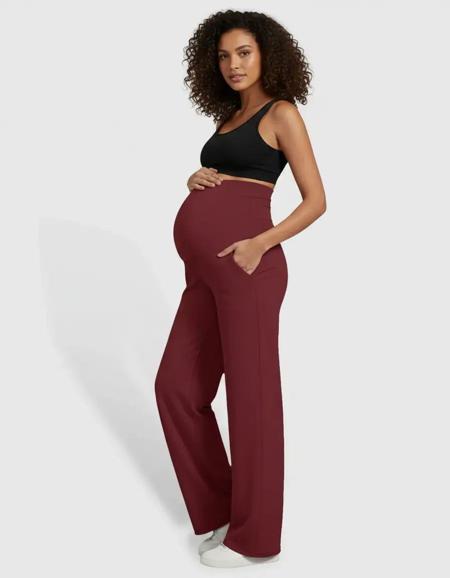 Pregnant woman in high-waist, straight-leg burgundy maternity pants with pockets and a black sports bra.