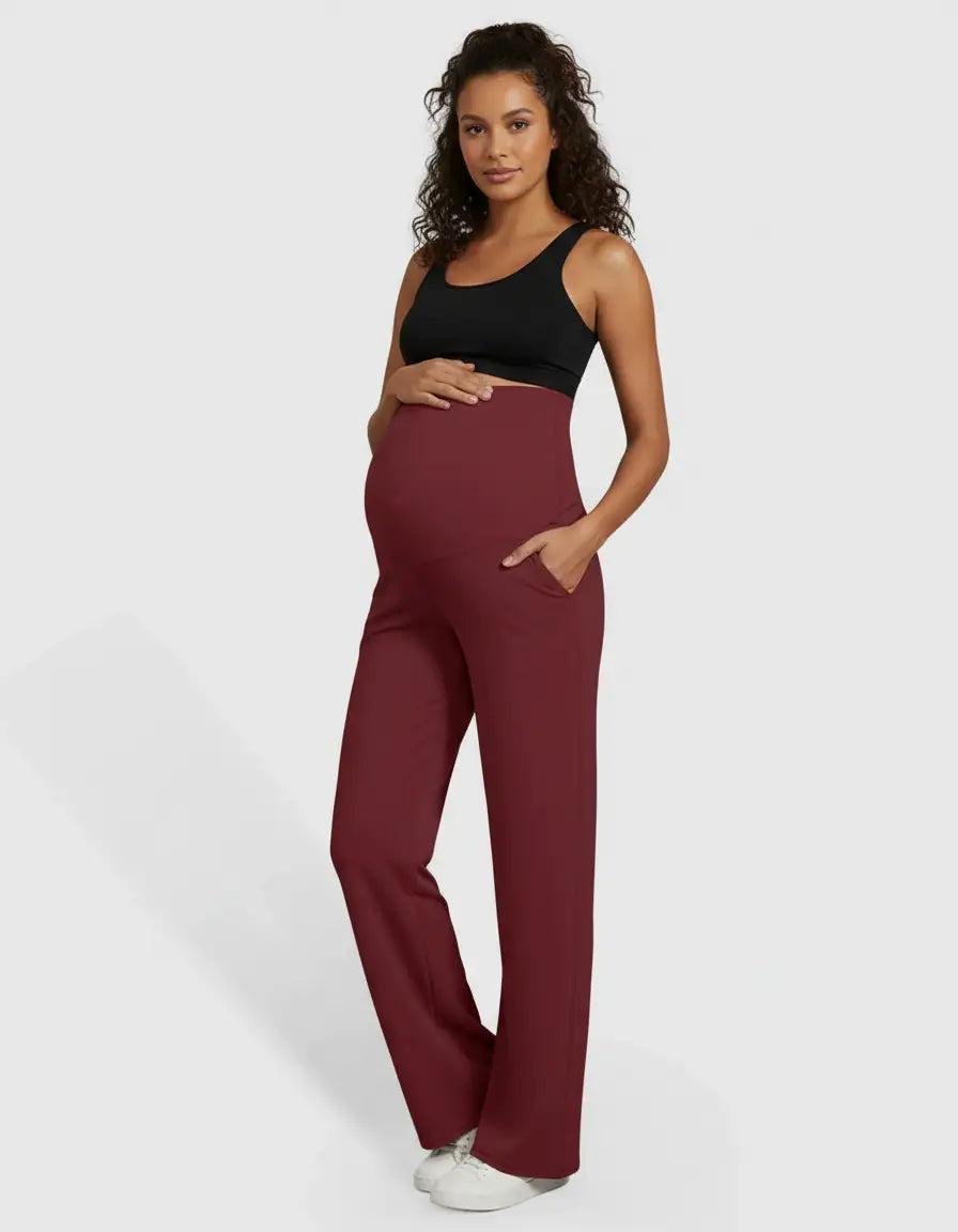Pregnant woman in high-waist, straight-leg burgundy maternity pants with pockets and a black sports bra.
