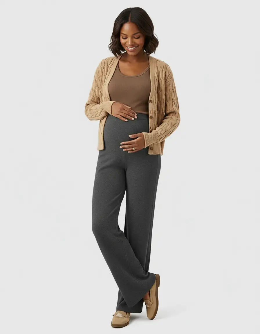 Smiling pregnant woman in dark gray high-waist wide-leg maternity wool pants and a tan cardigan.