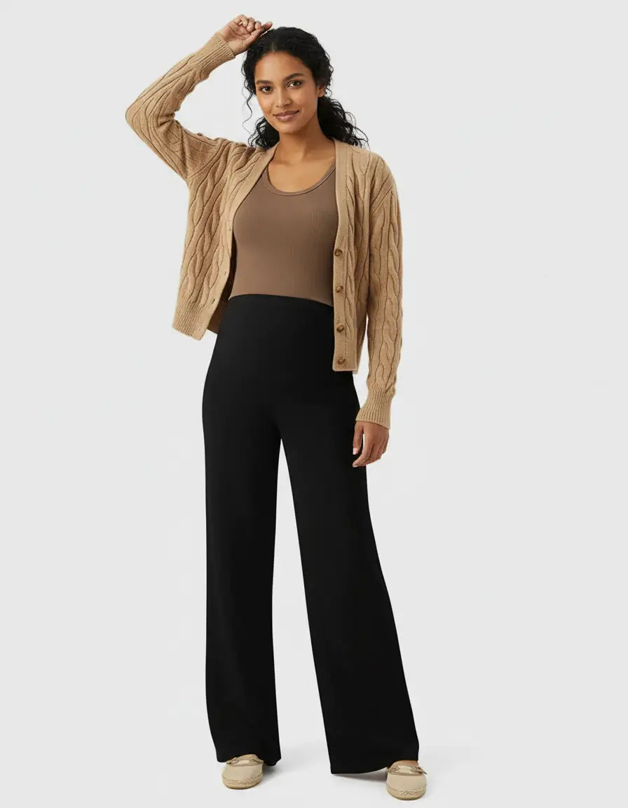 Woman in black high-waist wide-leg maternity wool pants, brown tank top, and cable-knit cardigan.