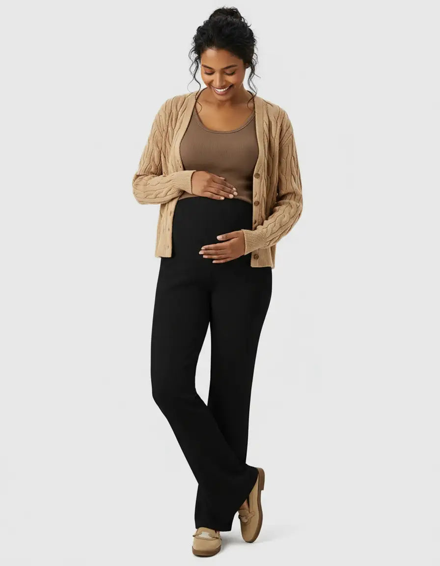 Smiling pregnant woman in black high-waist wide-leg maternity wool pants, brown tank, and cardigan.