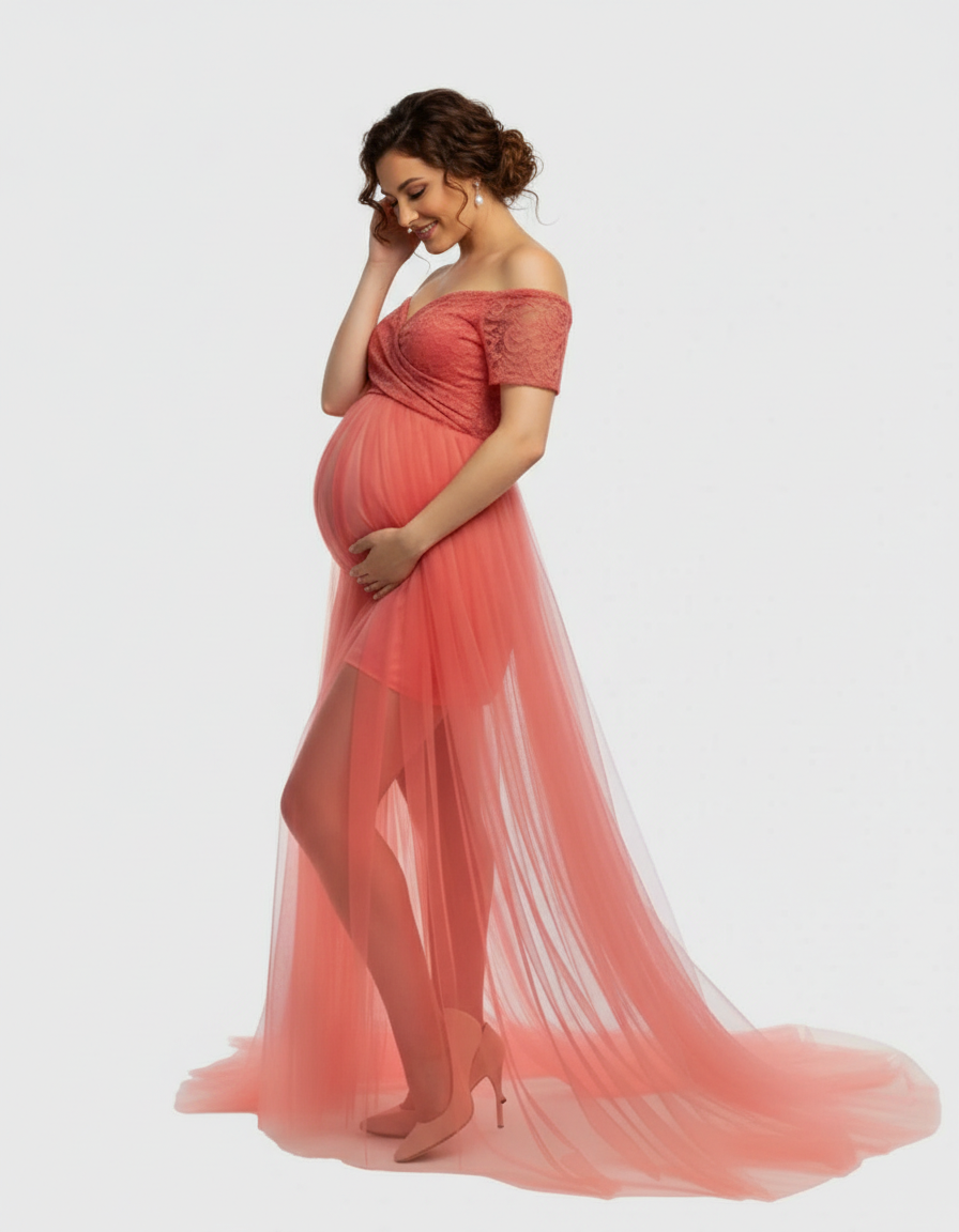 Smiling pregnant woman in a coral lace & mesh off-shoulder maternity gown with a flowing skirt.