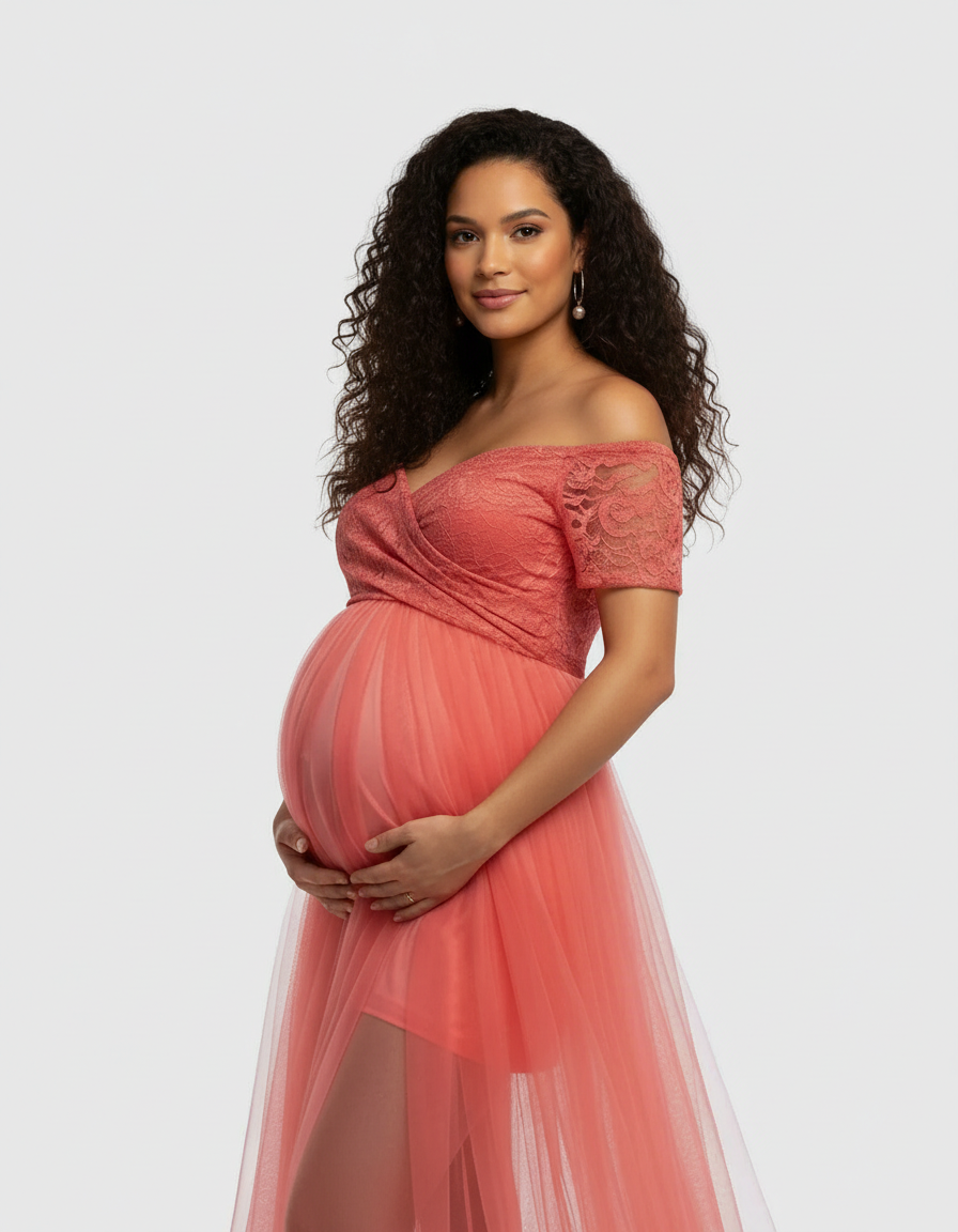 Maternity model in a coral lace and mesh off-shoulder gown, cradling her bump.
