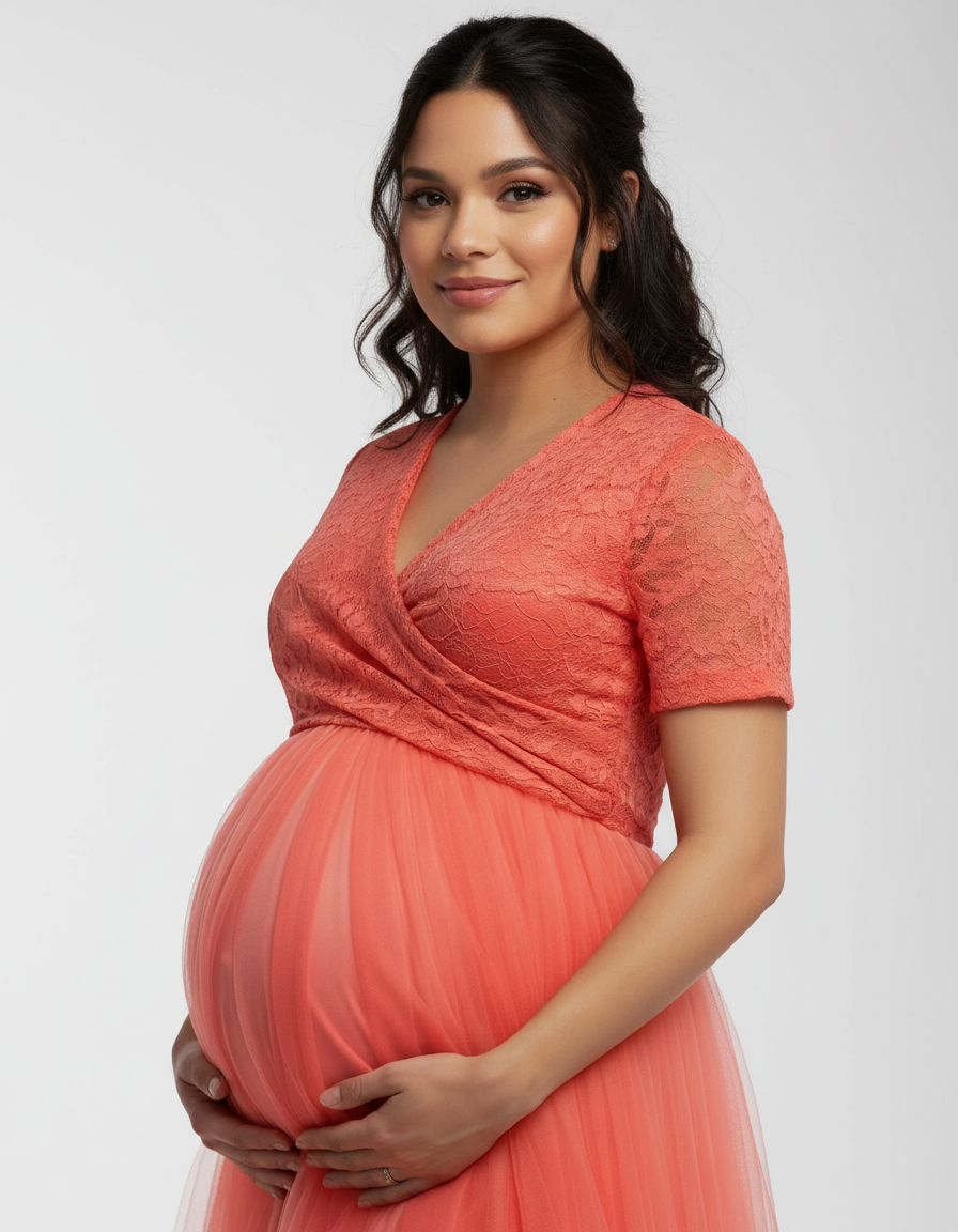 Smiling pregnant woman in a coral lace and mesh off-shoulder maternity gown.