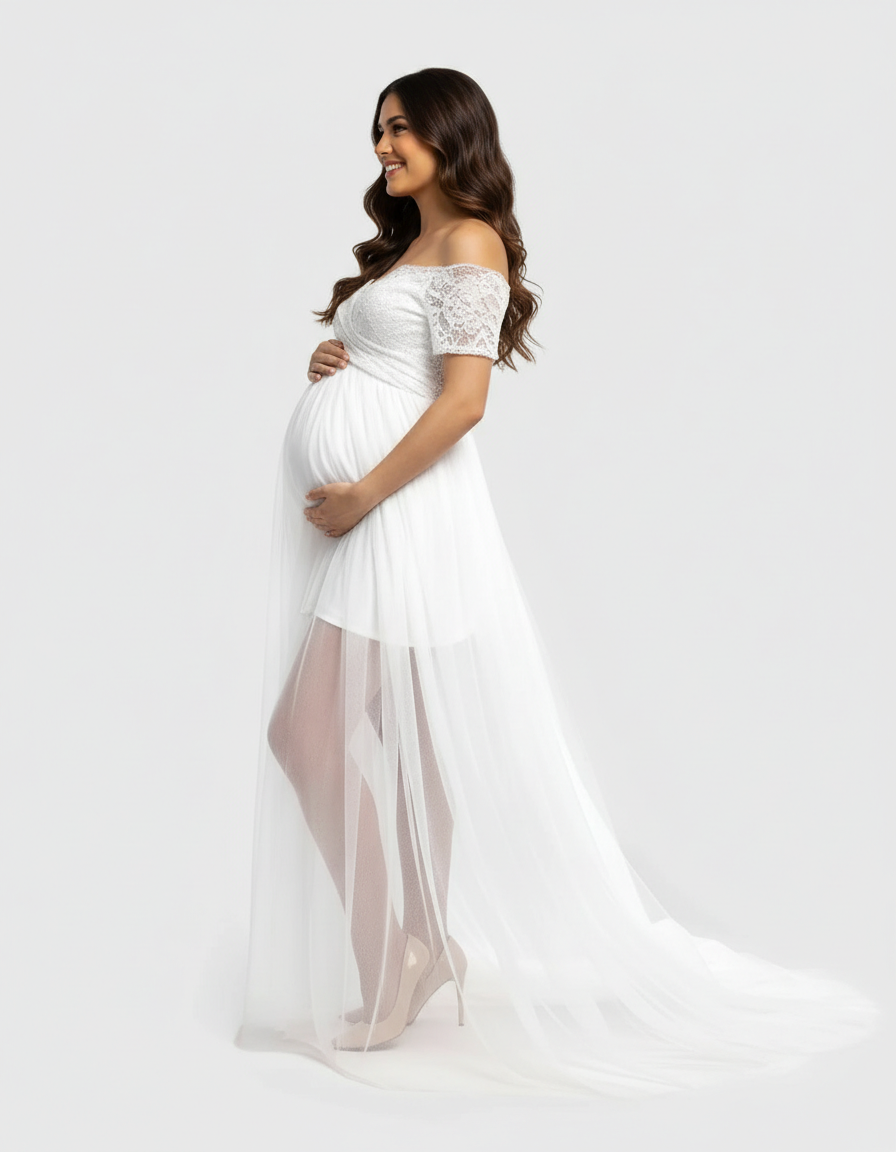 Pregnant woman in white lace & mesh off-shoulder maternity gown with long flowing skirt.