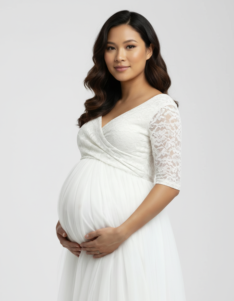 Pregnant woman in a white lace and mesh off-shoulder maternity gown, holding her belly.
