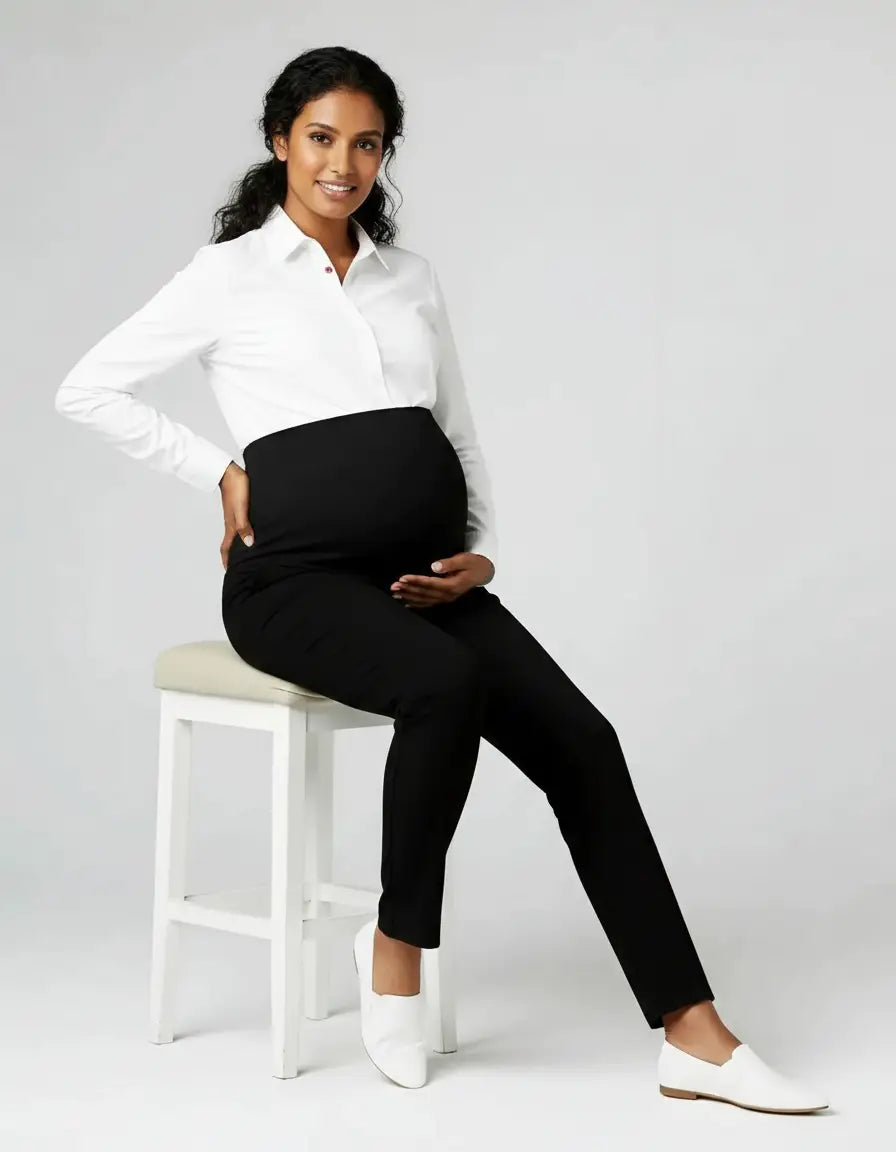 Smiling pregnant woman in black mid-waist straight-leg maternity work pants and white shirt.