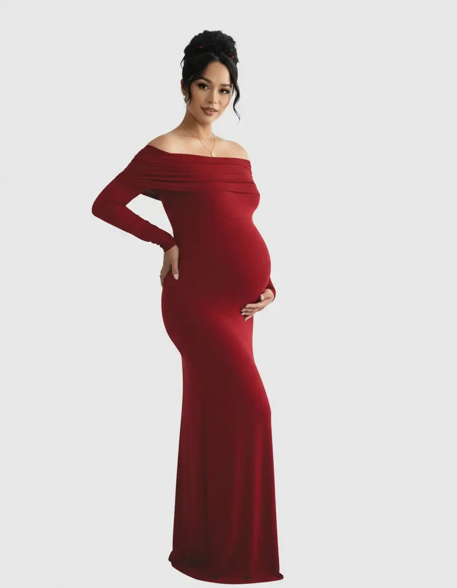 Pregnant woman in a long, flowing red off-shoulder cross-back maternity gown.