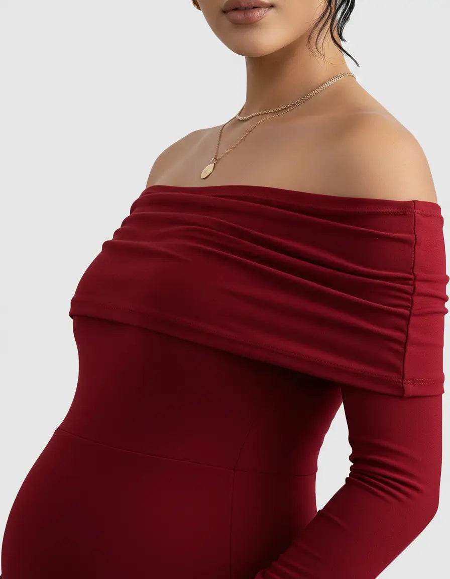 Close-up of a woman wearing a red off-shoulder cross-back maternity gown with a gold necklace.