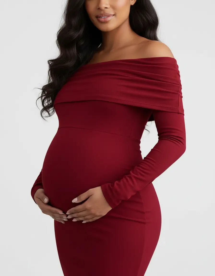 Maternity model in a long-sleeved, off-shoulder, cross-back, deep red gown, cradling her baby bump.