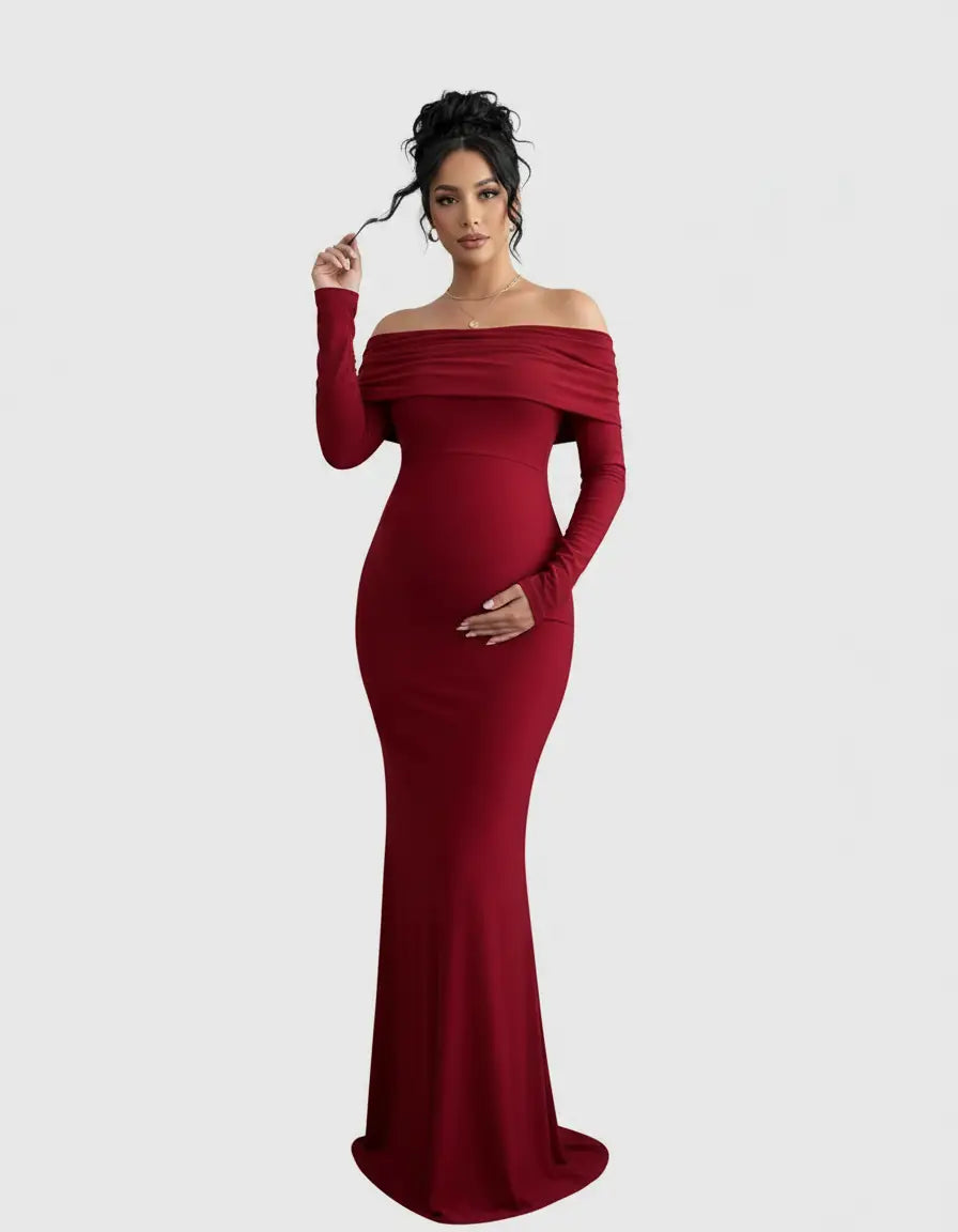 Pregnant woman in a long, form-fitting, off-shoulder cross-back maternity gown in deep red.